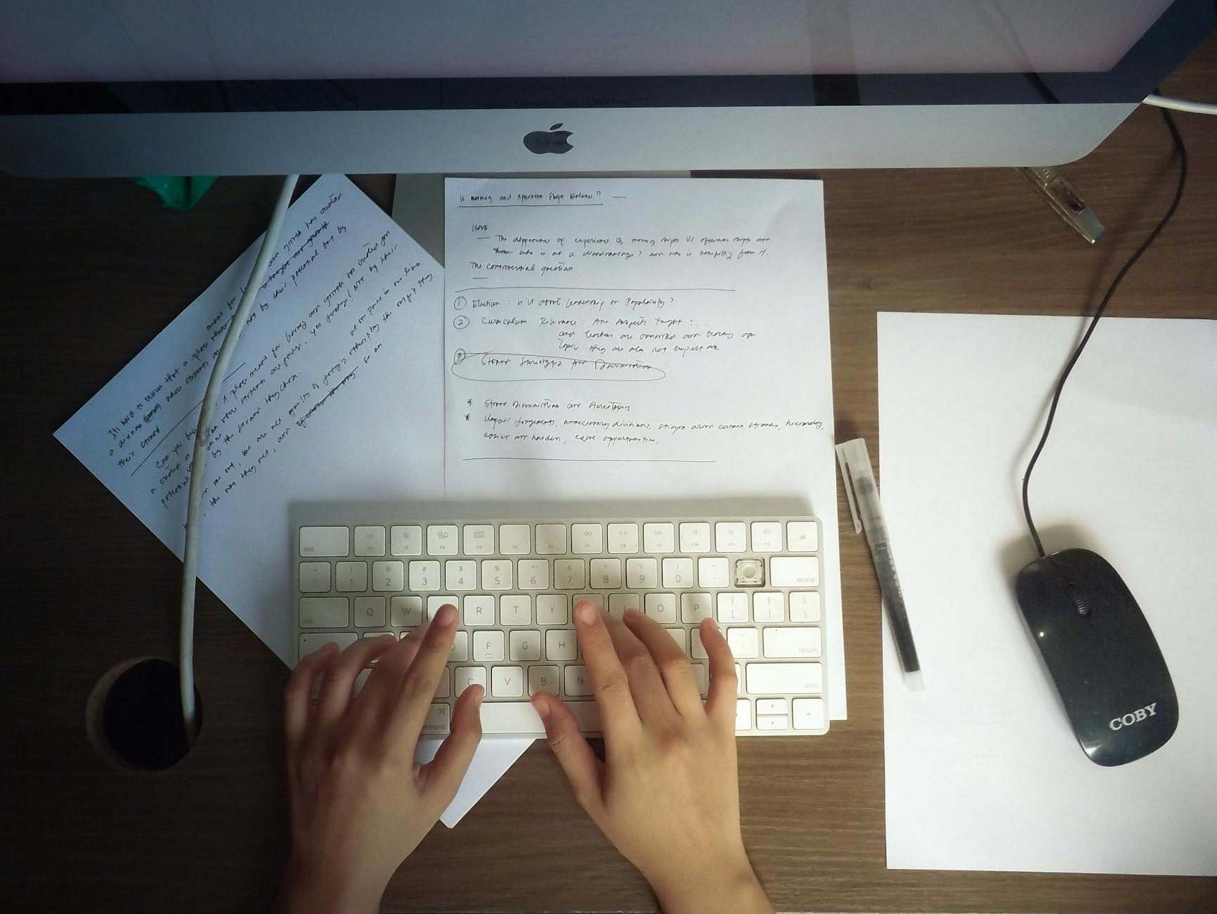 Dłonie piszące na klawiaturze komputera przy drewnianym biurku