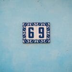 Niebieska tabliczka z numerem 69 na fakturowanej niebieskiej ścianie