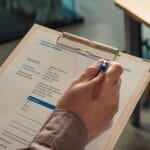 Kiedy NIP na fakturze nie pasuje do nazwy firmy i co z tym zrobić Dłoń trzymająca fakturę firmy na clipboardzie z długopisem