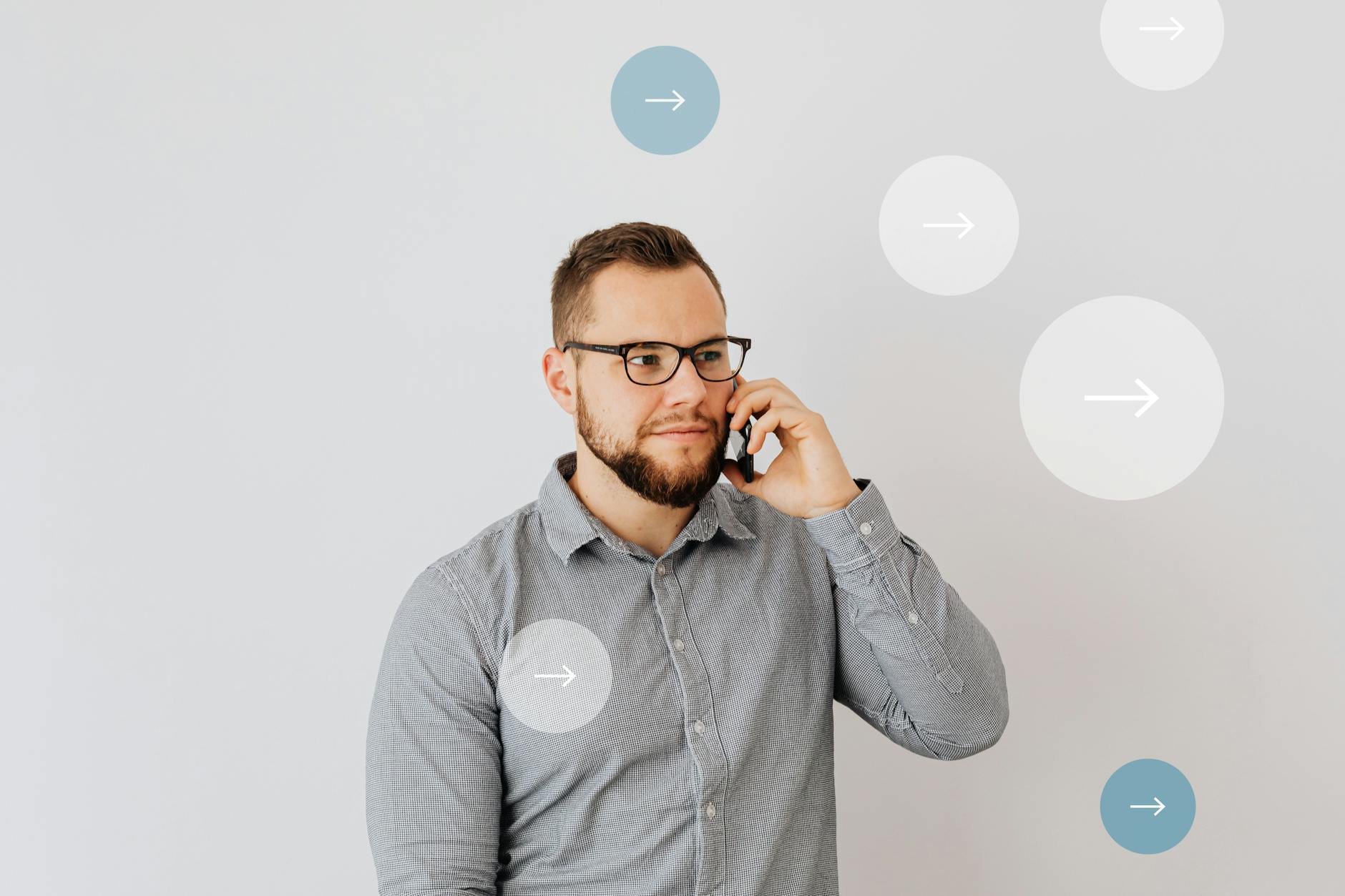 Mężczyzna w biurze rozmawia przez telefon, na tle strzałki symbolizujące kontakt