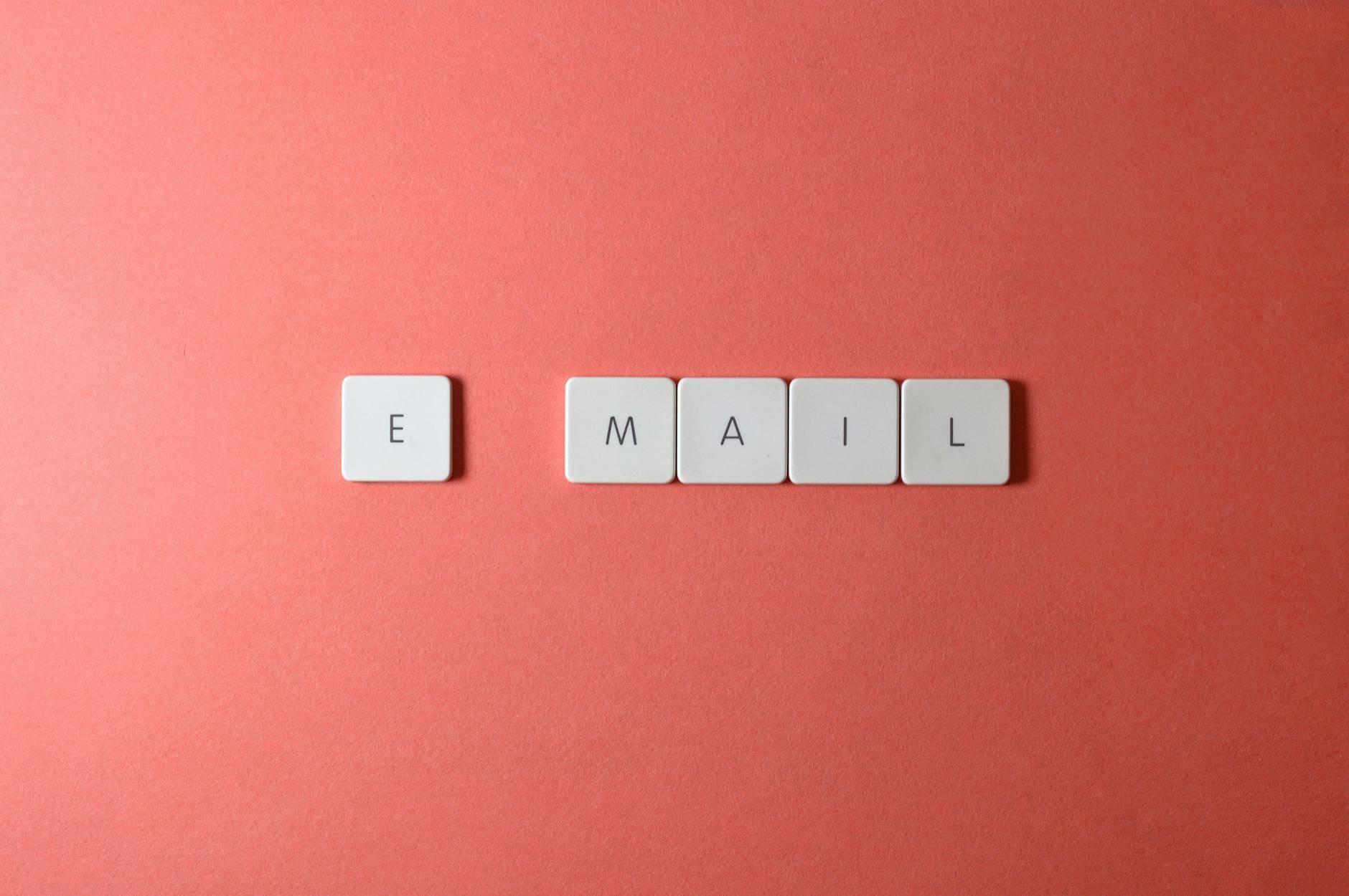 Białe literki układające się w słowo email na koralowym tle