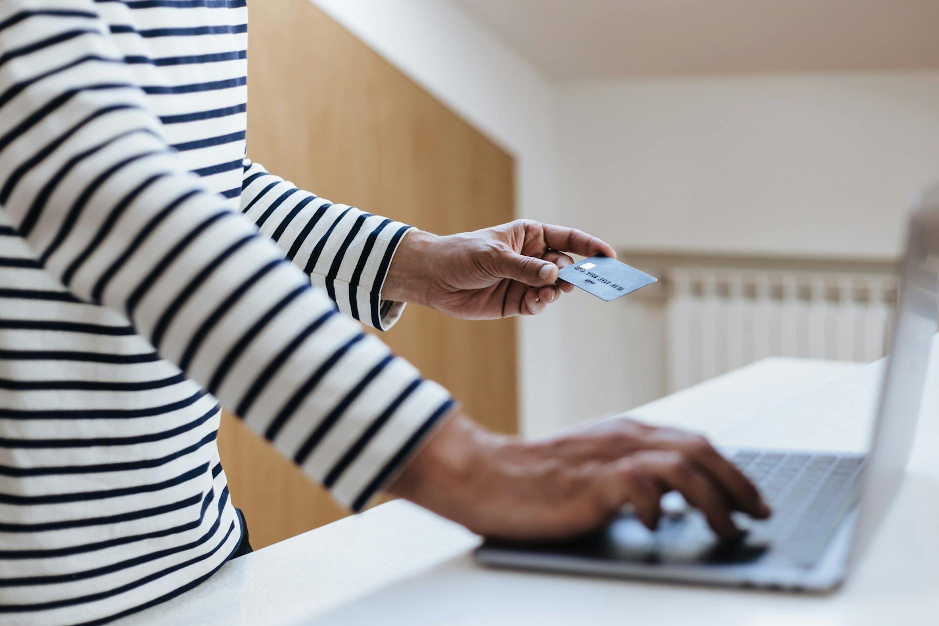 Osoba płaci kartą kredytową za zakupy online na laptopie