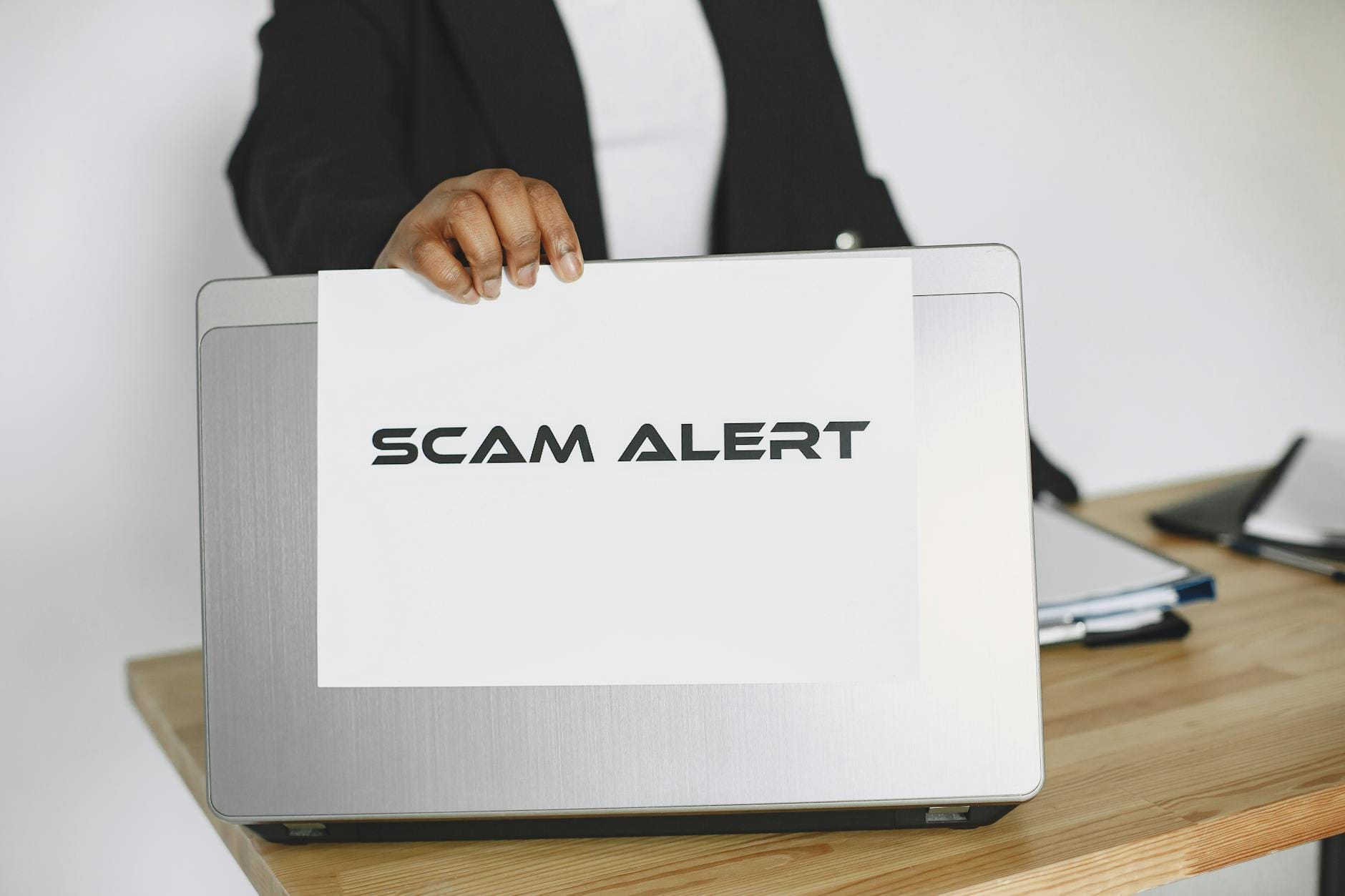 Przedsiębiorca trzyma kartkę scam alert nad laptopem z danymi firmy CEIDG