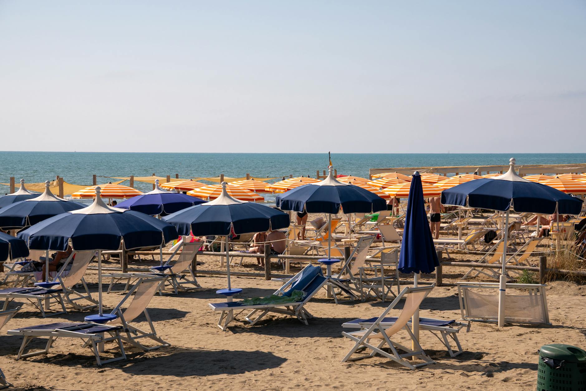 Słoneczna włoska plaża z kolorowymi parasolami i leżakami