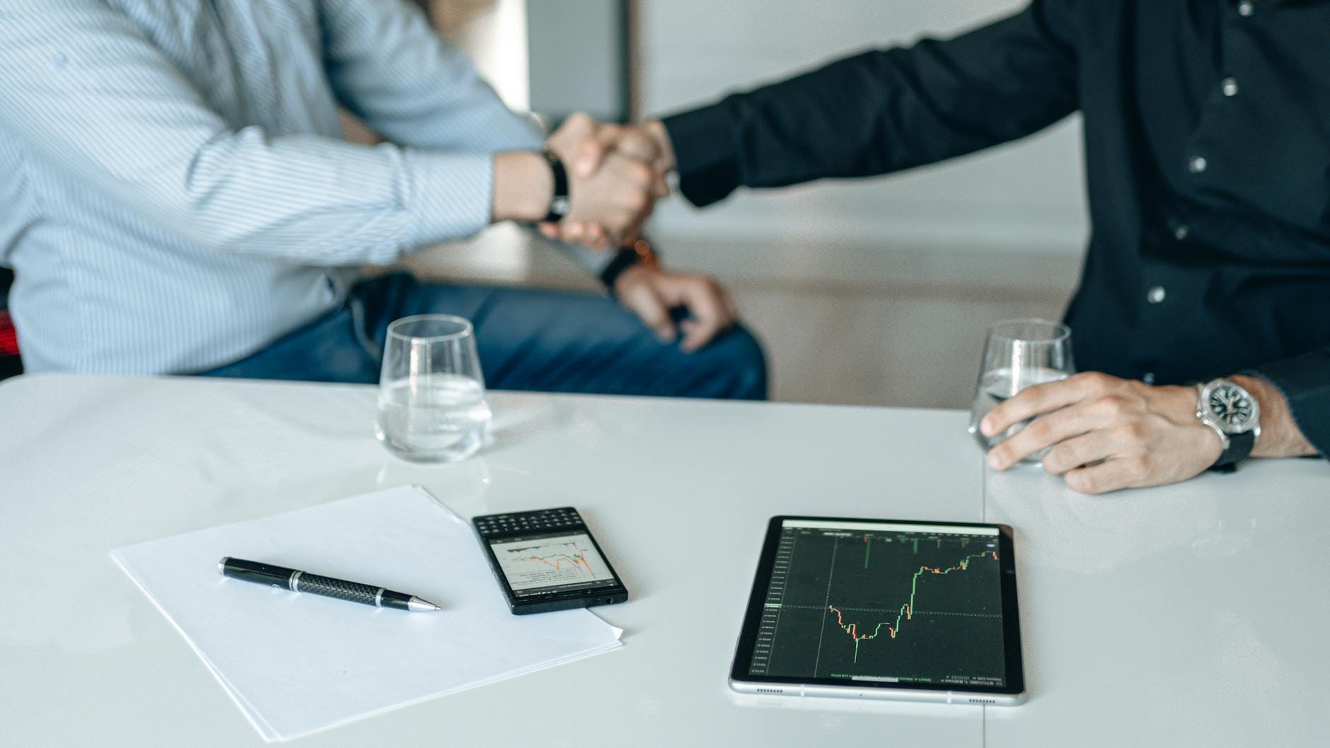 Uścisk dłoni wspólników nad tabletem z analizą finansową