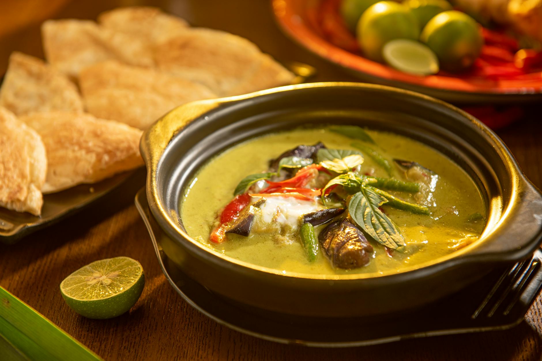 Zielone tajskie curry z warzywami i ziołami podane w czarnej misce