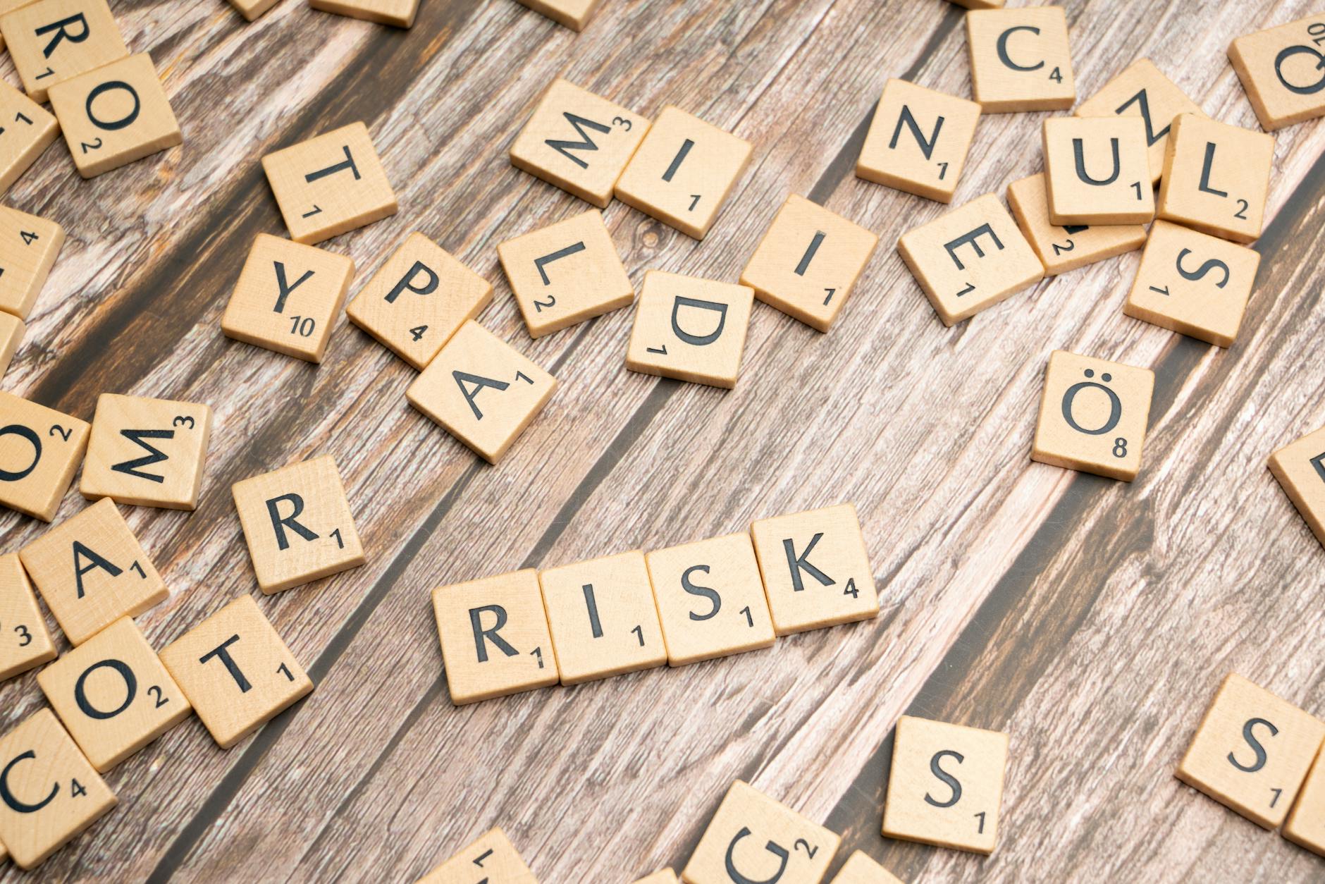 Drewniane klocki z napisem risk na rustykalnym tle symbolizujące ryzyko