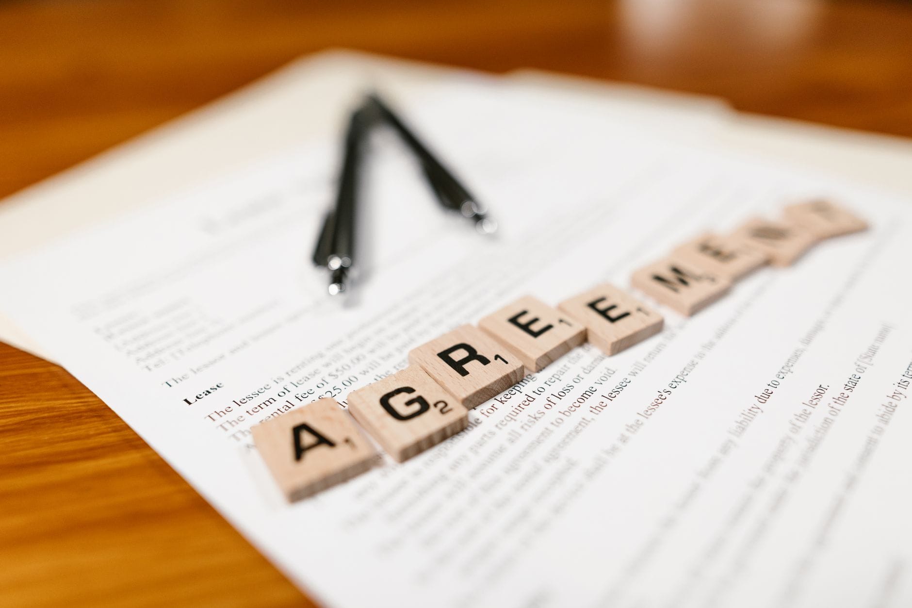 Kafelki Scrabble układające się w słowo AGREEMENT na dokumencie umowy