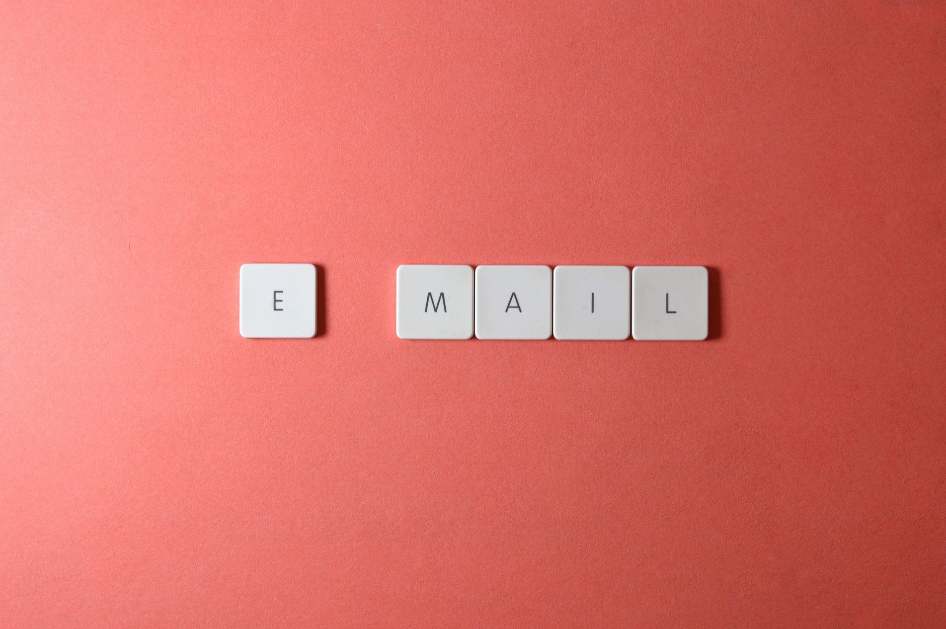Białe kostki z literami układającymi się w słowo email na koralowym tle