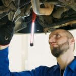 Mechanik podniesionego auta sprawdza podwozie w warsztacie samochodowym