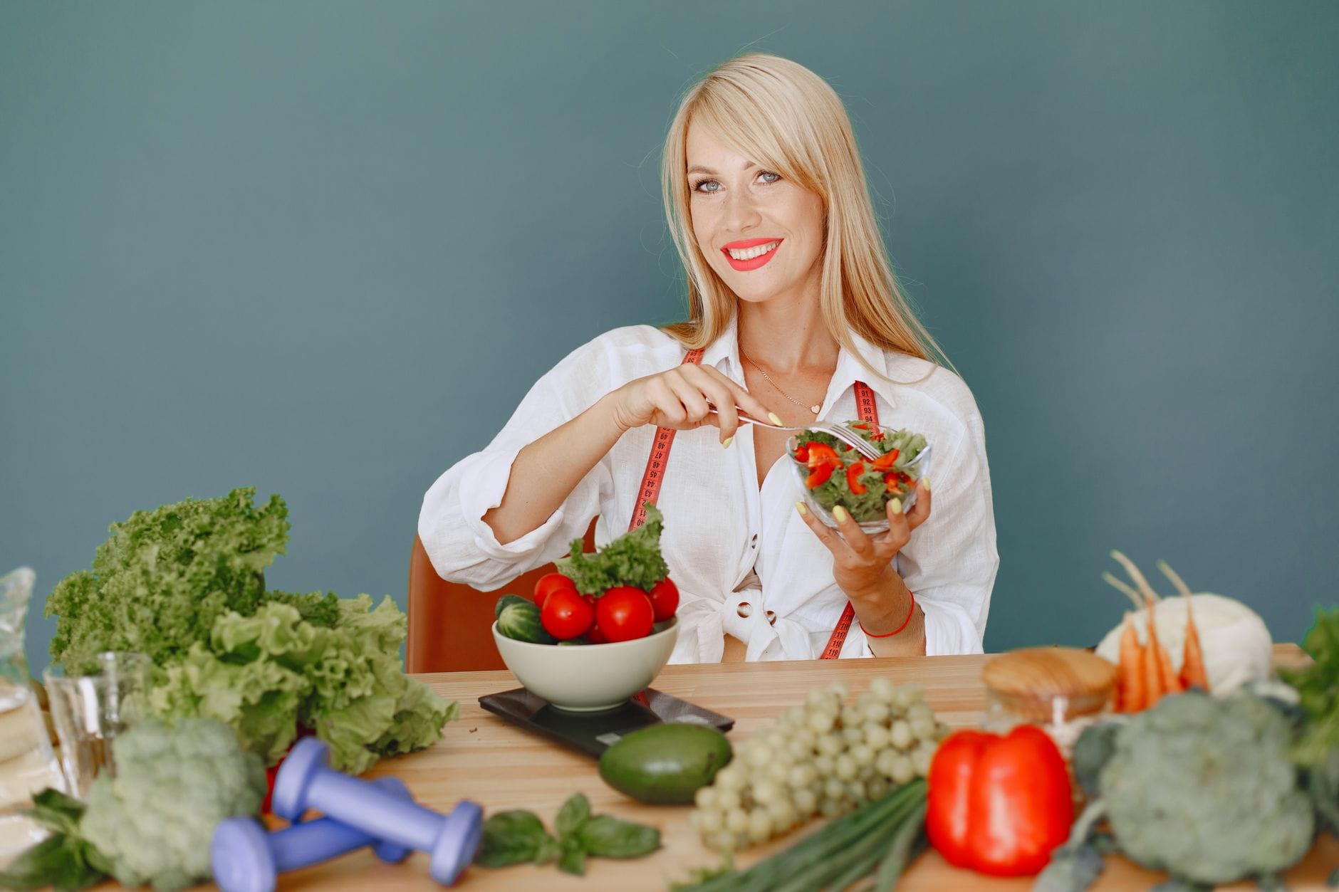 Blondynka je świeżą sałatkę, na stole leżą warzywa