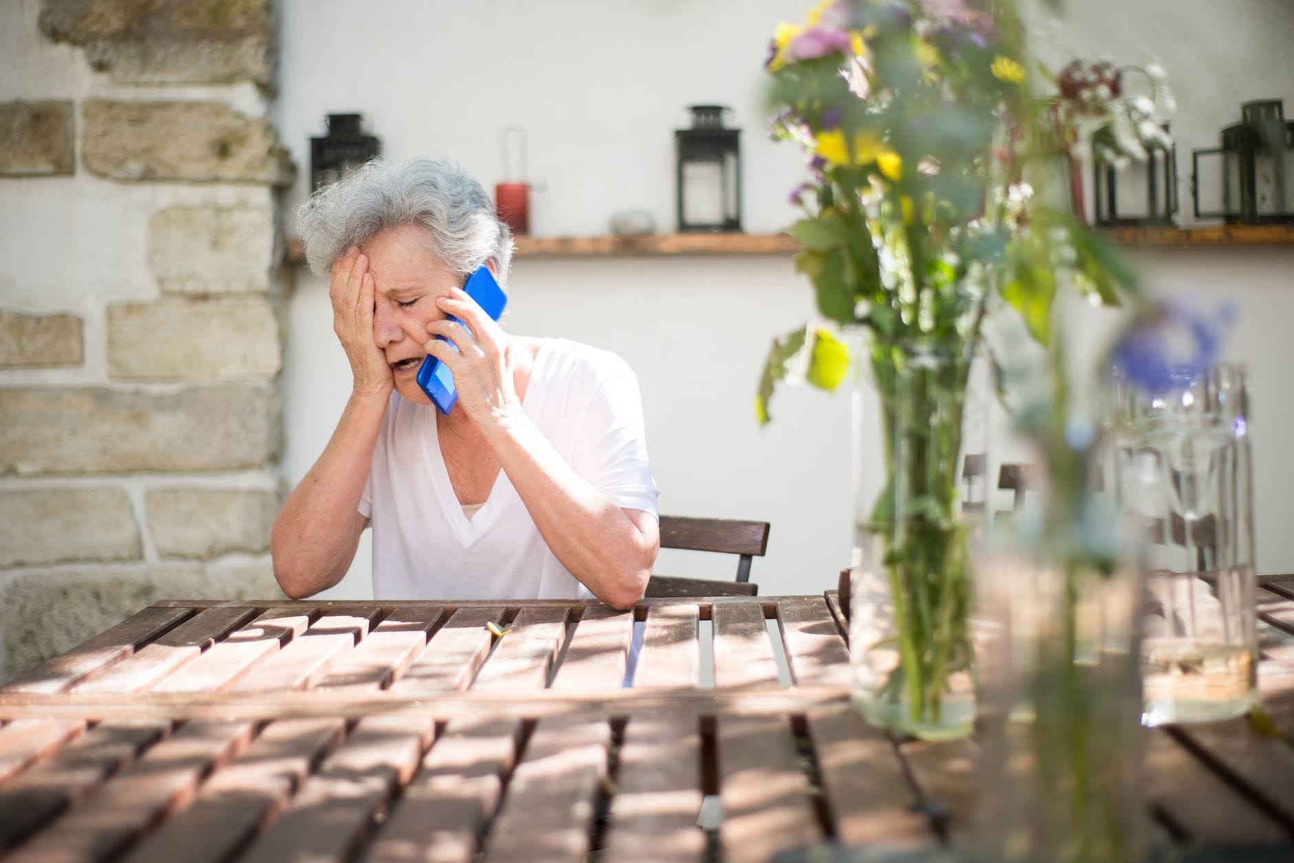 Starsza zaniepokojona kobieta na zewnątrz patrzy w telefon