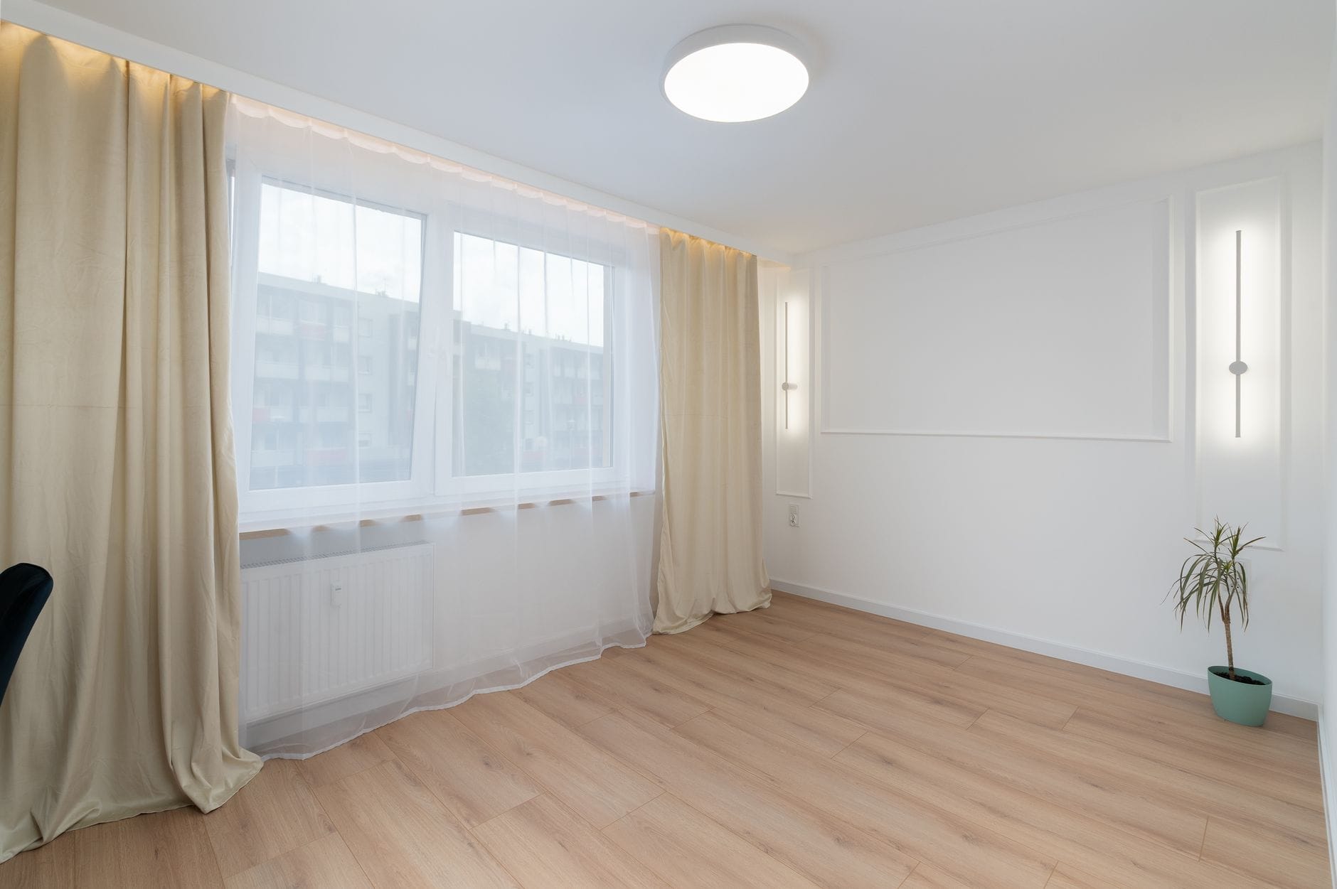 Jasny minimalistyczny salon w Krakowie z dużym oknem i drewnianą podłogą