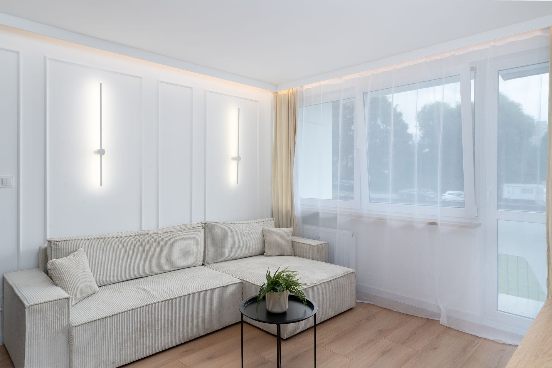 Jasny minimalistyczny salon z nowoczesnym oświetleniem i wygodną sofą
