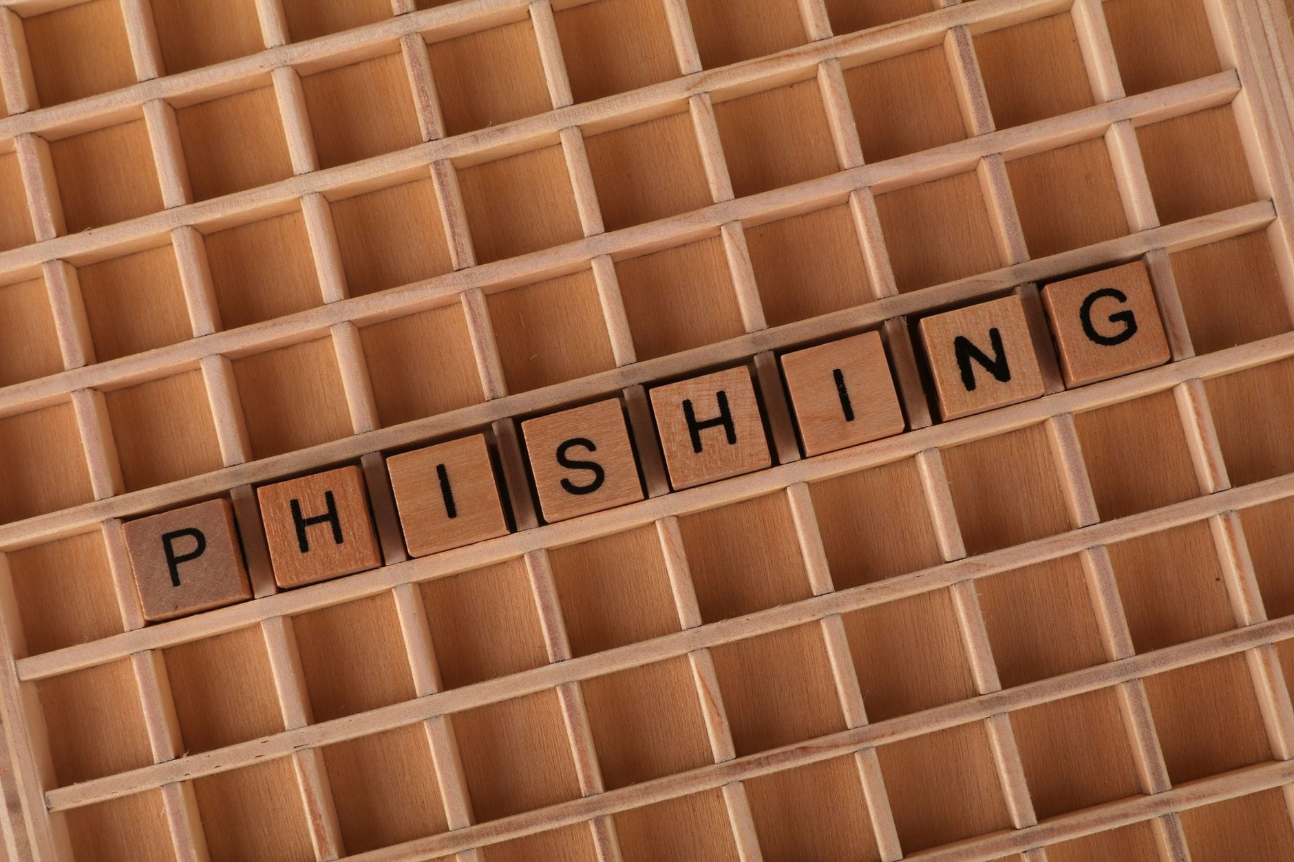 Klocki Scrabble układające się w słowo phishing na drewnianym tle