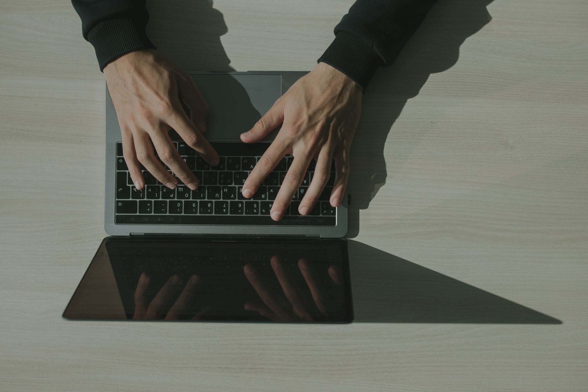 Ręce na klawiaturze laptopa podczas pracy nad weryfikacją firmowego maila
