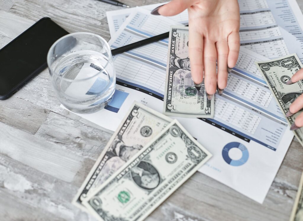 Dokumenty finansowe z dolarami i szklanką wody widziane z góry